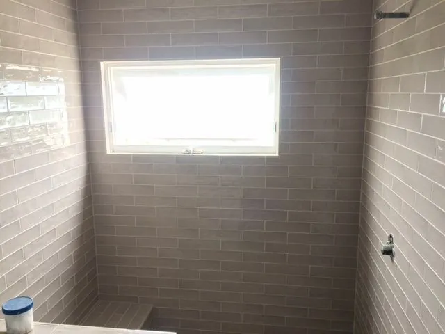 Shower walls in gray glazed subway tile around a window