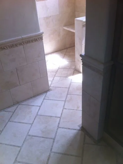 Bathroom with diagonal limestone floor tile and a wall tile band with a decorative border