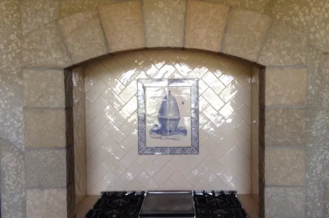 Range niche in white herringbone tile with a Delft-style tile accent under a stone arch