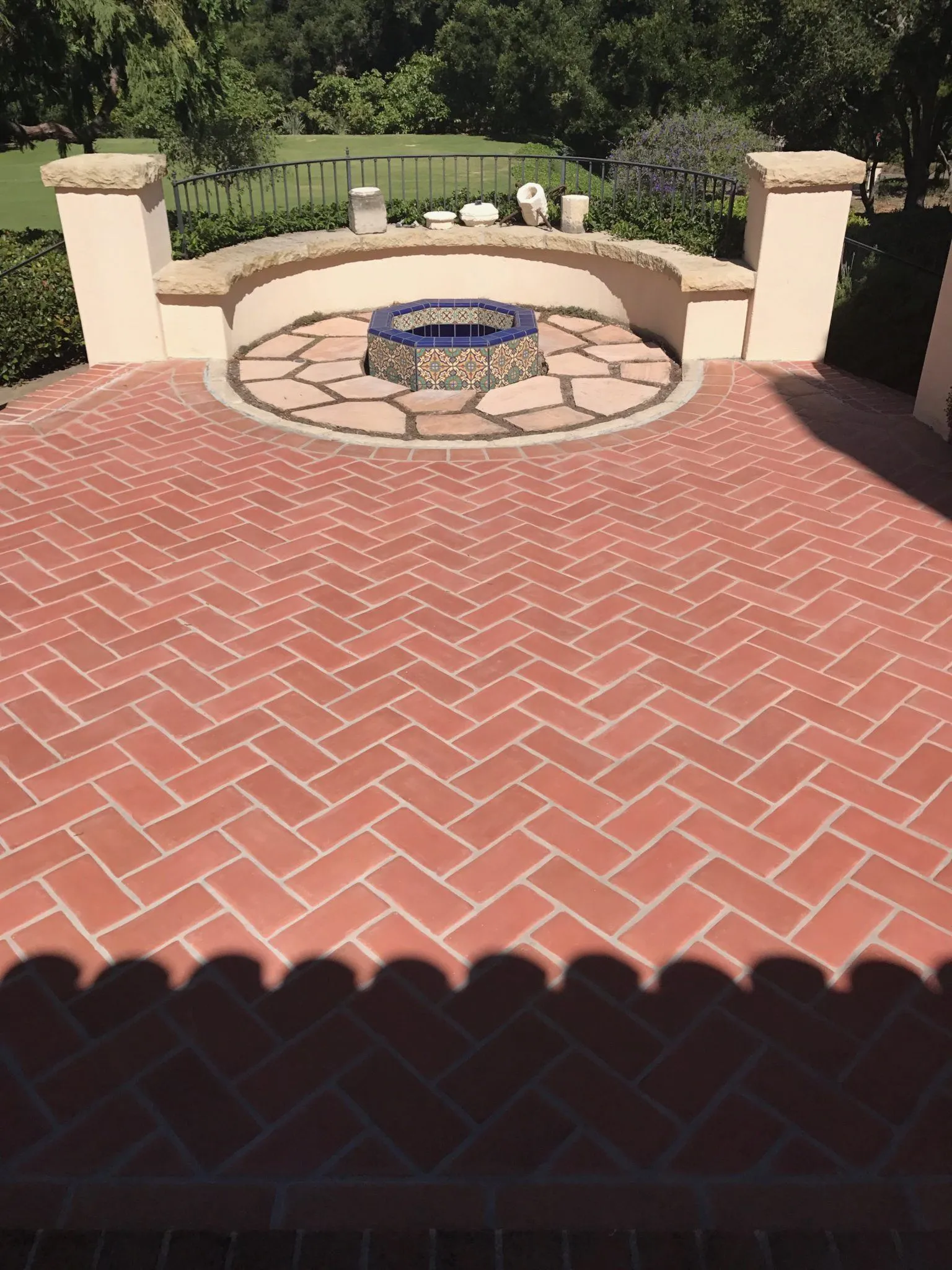 Red brick herringbone patio around a fire pit with a circular stone surround